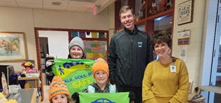 kids and adults holding green banner showing images of bikes, cars and the word safe